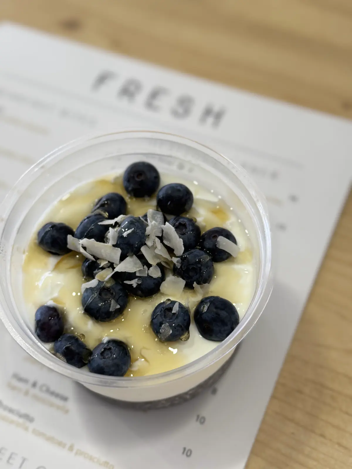 Chia pudding with Greek yoghurt, blueberries, coconut and honey in a takeaway cup