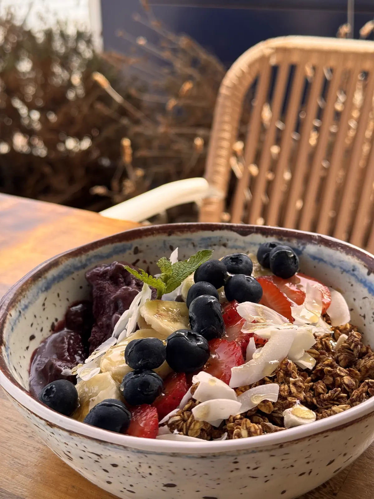 Açaí bowl orgánico con granola, plátano, fresas y arándanos en la terraza